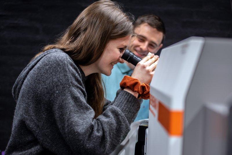 Kvinde kigger i et mikroskop