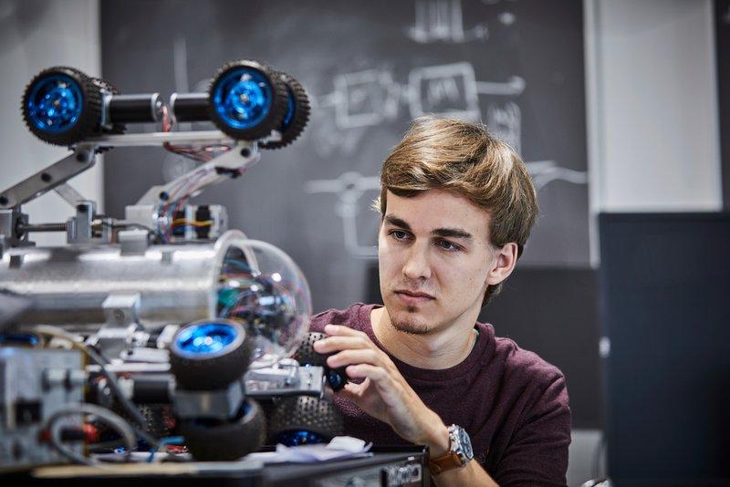 et billede, en person af hankøn arbejder på noget mekanik